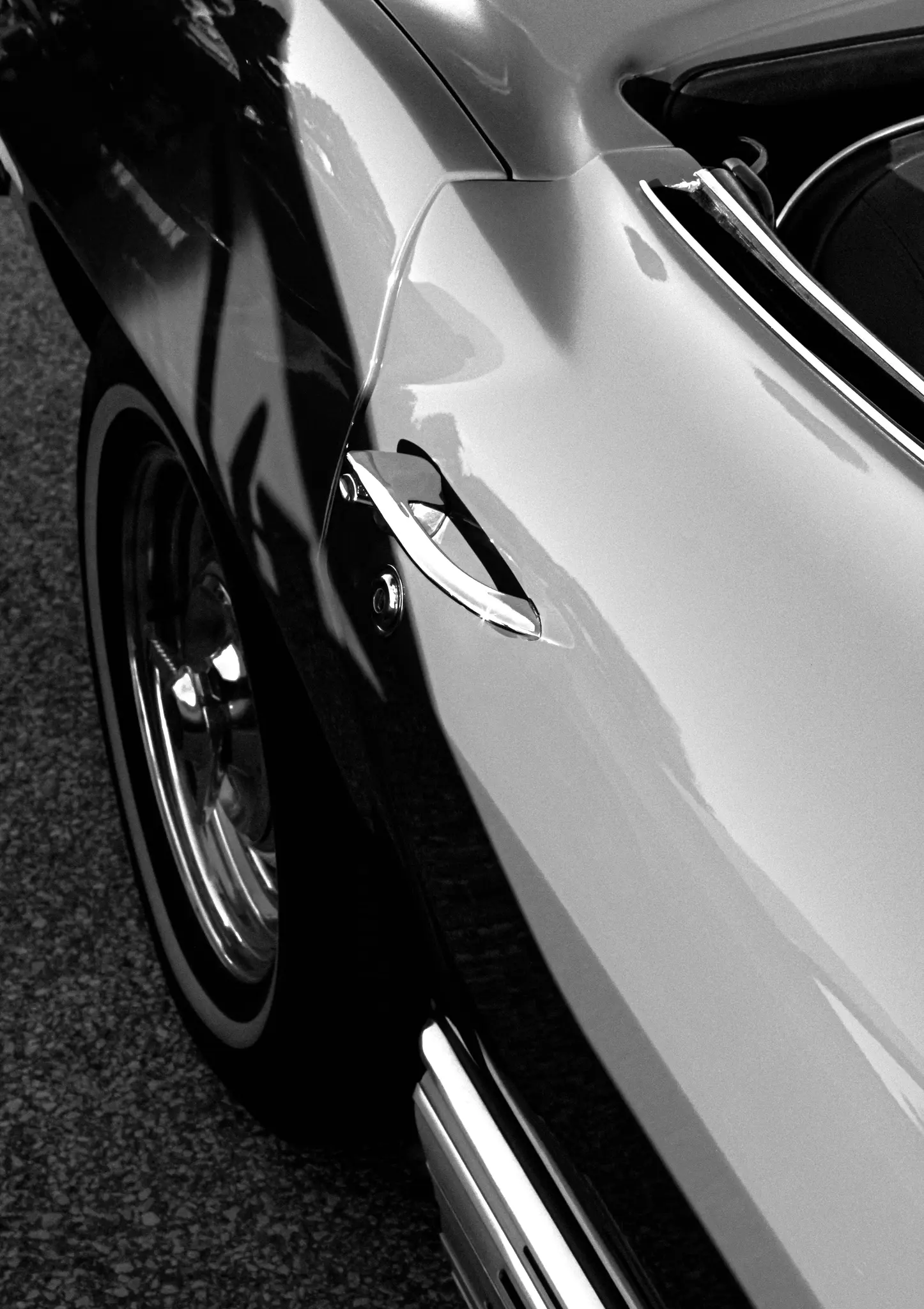 Primo piano in bianco e nero del lato di un'auto d'epoca, che mostra la maniglia cromata della portiera, il parafango