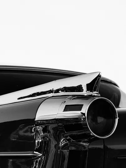 Un primer plano en blanco y negro de la parte trasera de un coche clásico, que muestra una prominente aleta trasera y una luz