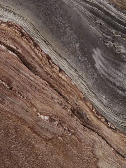 A close-up abstract image of a surface with diagonal lines and textures in shades of brown, red, and gray.