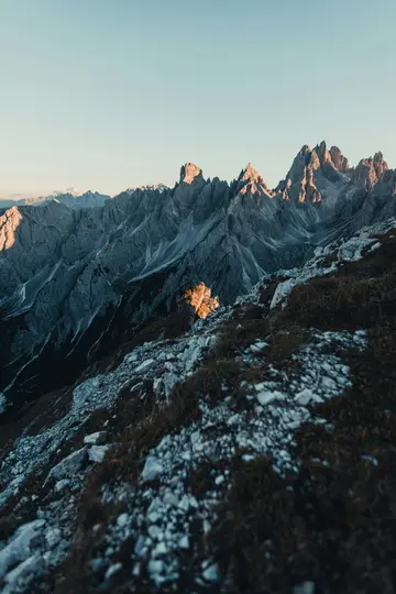 Una impresionante fotografía de paisaje que muestra picos montañosos grises y escarpados iluminados por una luz dorada bajo