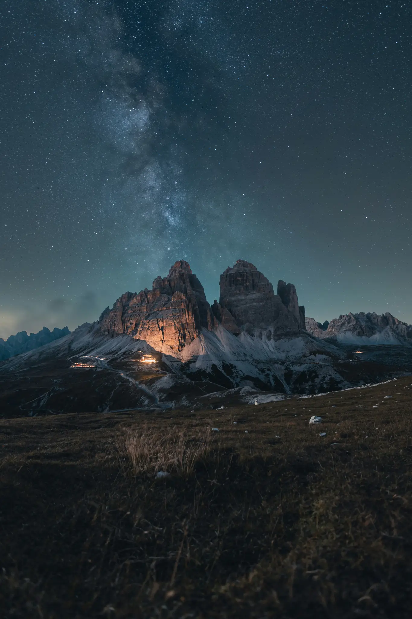 Un impresionante paisaje nocturno muestra la Vía Láctea arqueándose sobre escarpados picos montañosos, uno de los cuales está