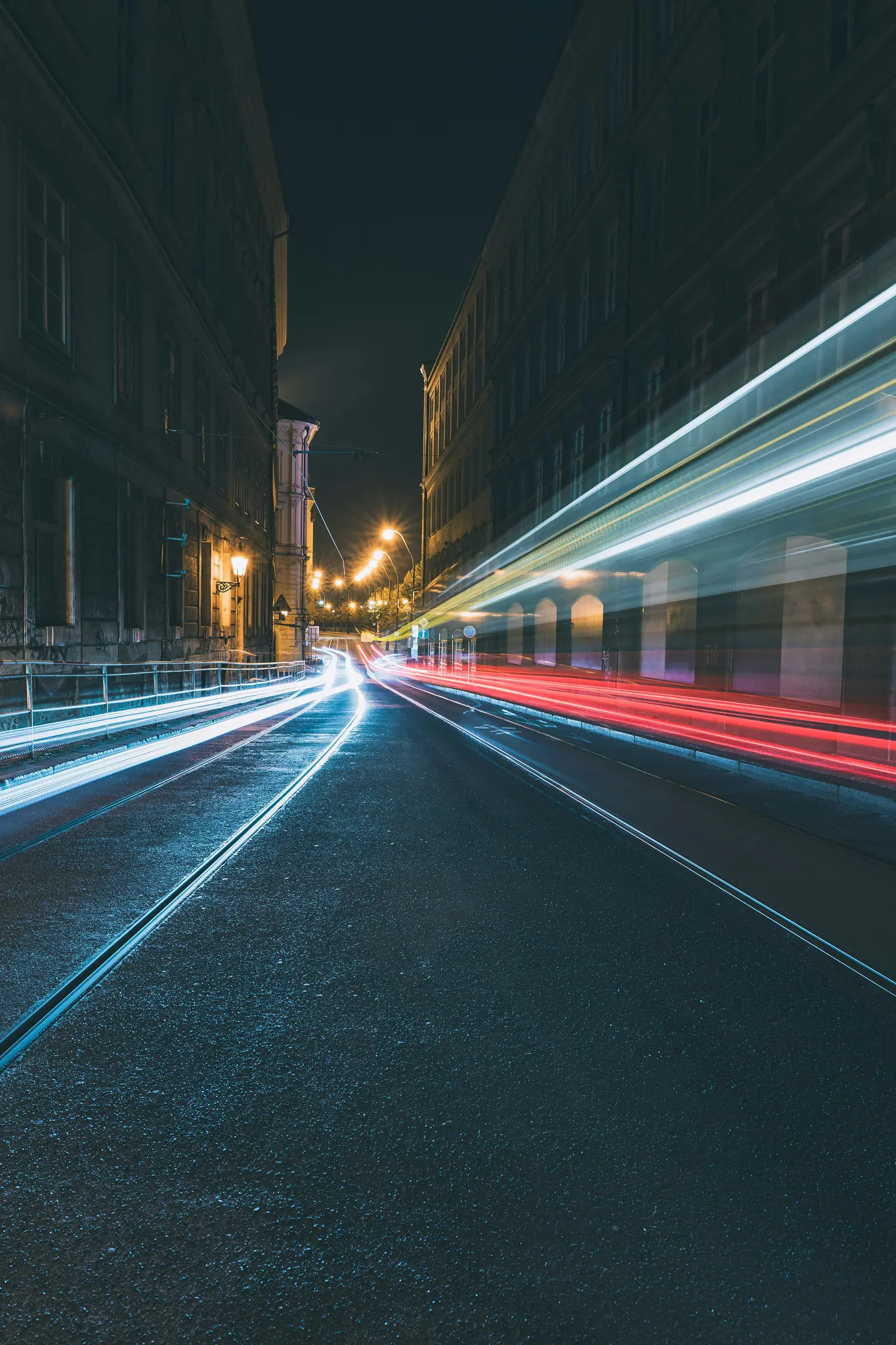 Eine Langzeitbelichtungsaufnahme einer dunklen Stadtstraße bei Nacht mit hellen roten und weißen Lichtspuren von