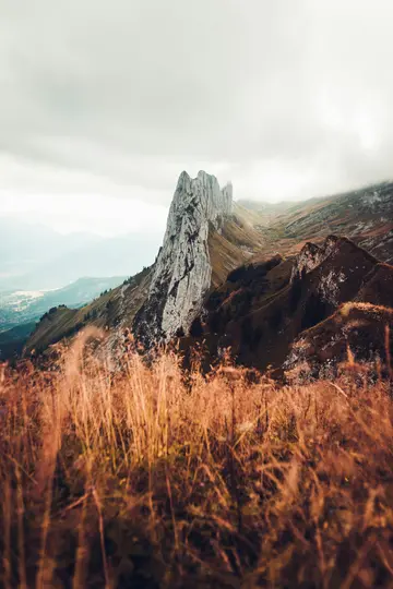 Una vista impactante de una formación rocosa alta, dentada y de color claro que se eleva desde una cresta montañosa, con
