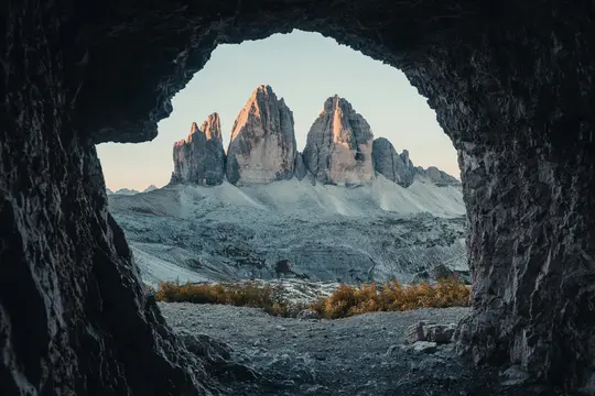 Una vista majestuosa de tres picos montañosos imponentes y escarpados, iluminados por la luz del atardecer, enmarcados por la