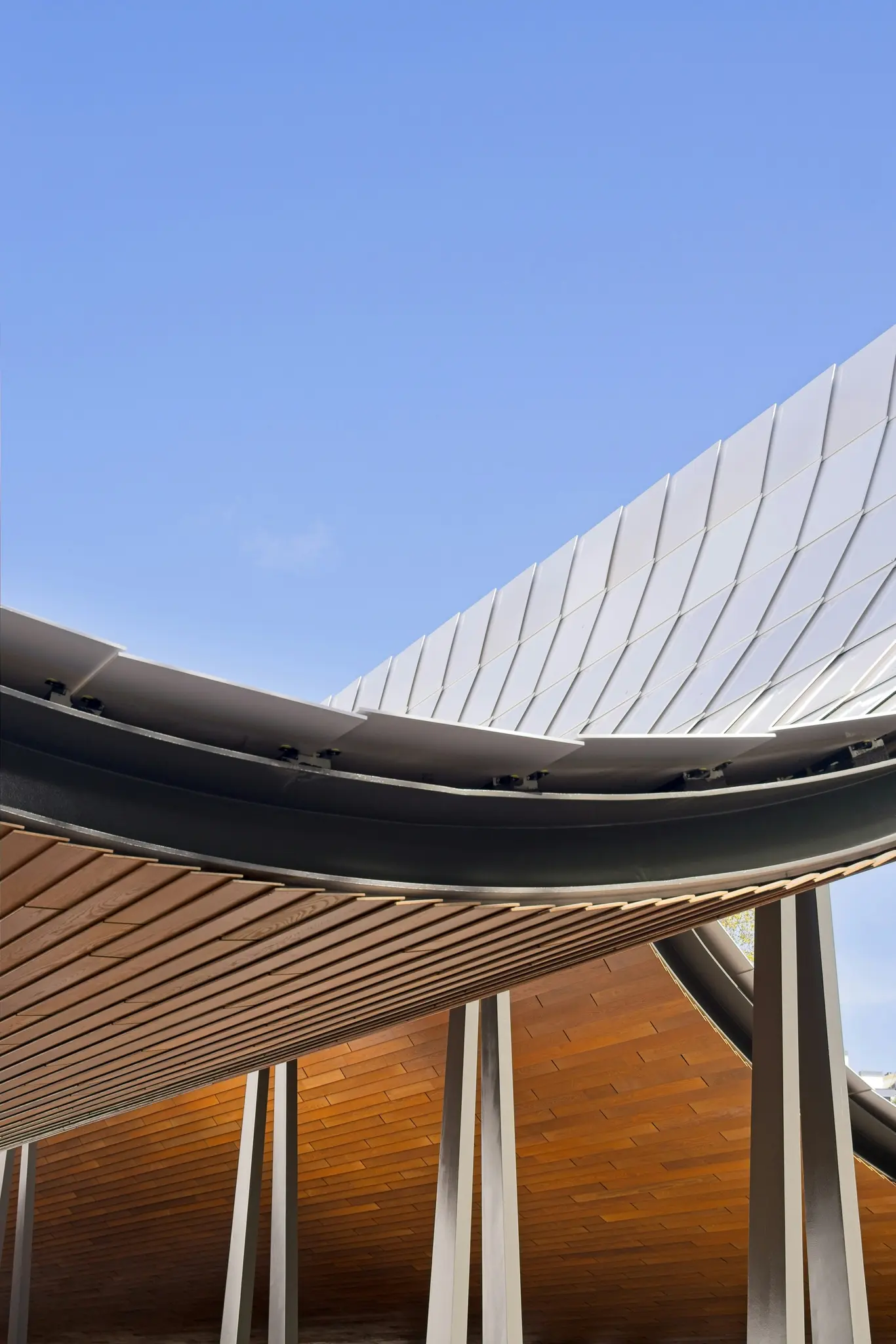 Detailný záber z nízkeho uhla na modernú architektonickú štruktúru s jasne modrou oblohou v pozadí. Štruktúra…