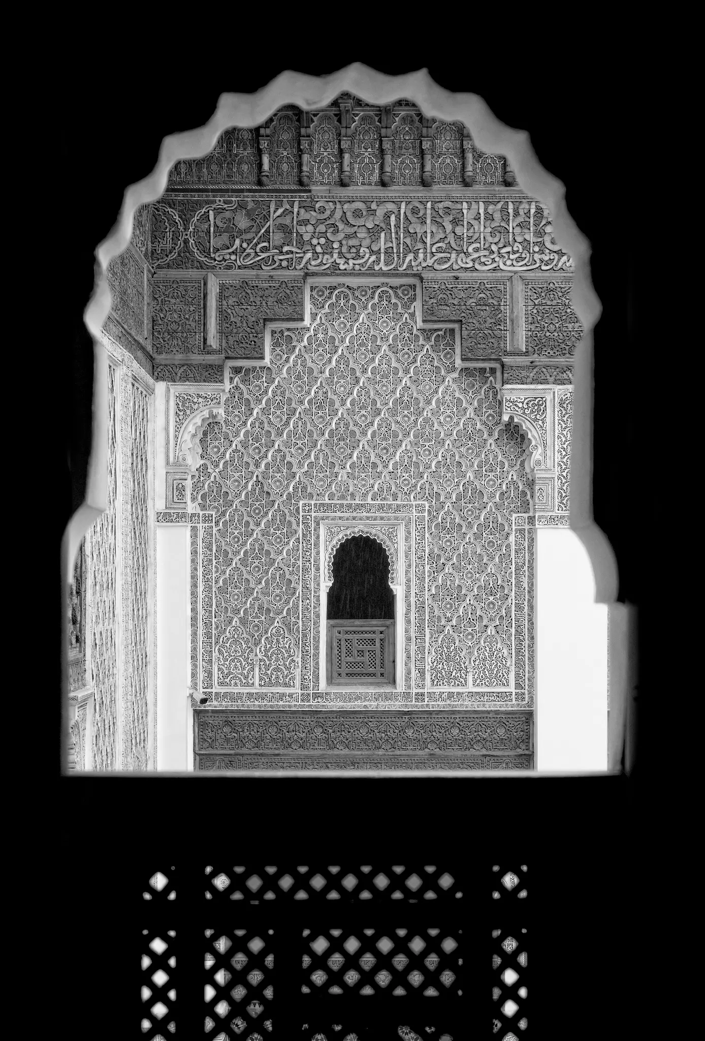 Una foto en blanco y negro que muestra una pared ornamentada y tallada a través de una puerta oscura y arqueada. La pared