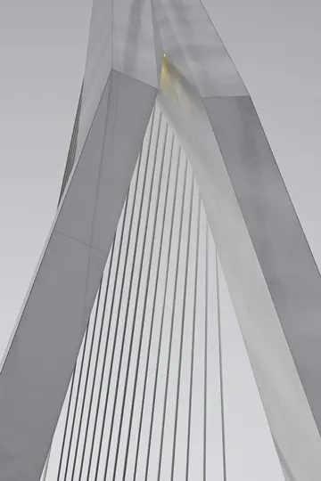 Eine abstrakte, nach oben gerichtete Nahaufnahme einer modernen Brücke mit eckigen grauen Stützen und zahlreichen parallelen