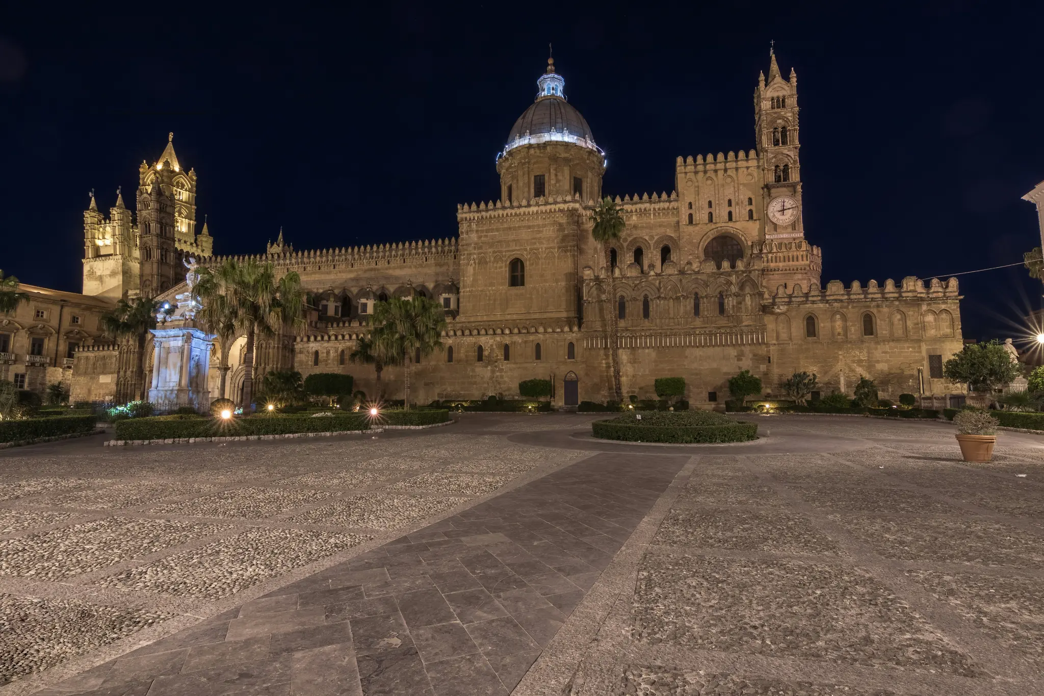 Una ripresa ampia dell'illuminata Cattedrale di Palermo di notte, con la sua architettura intricata e la cupola su uno sfondo