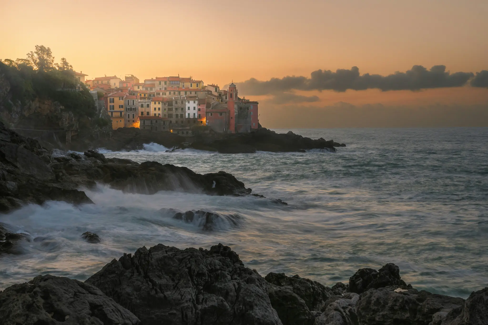 Un pittoresco villaggio costiero con edifici colorati su una scogliera rocciosa, affacciato sul mare con onde che si