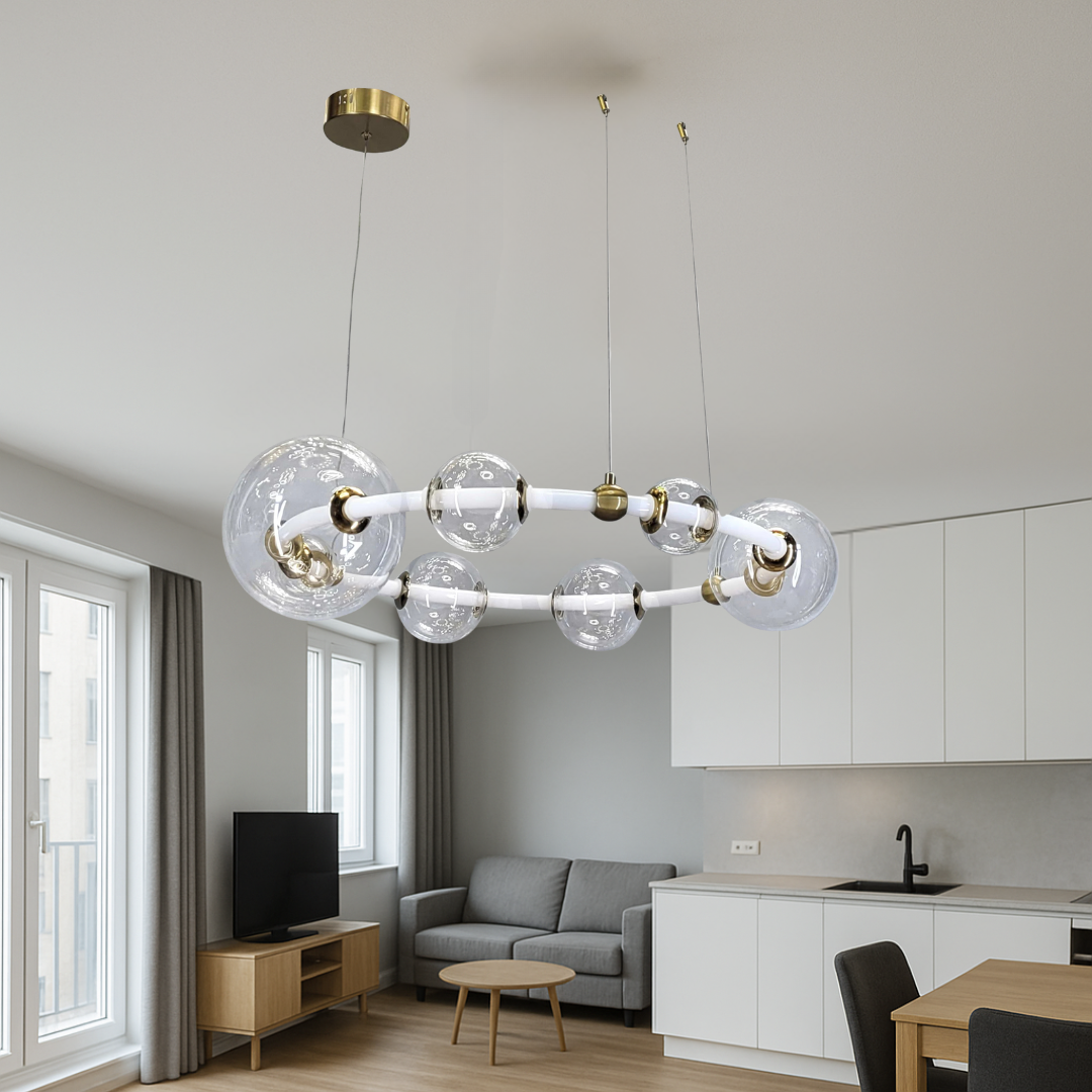 Підвісна світлодіодна люстра з білою та латунною основою, великим кільцем і скляним плафоном, рівномірно освітлює кухню-вітальню, підкреслює сучасний стиль та затишок.