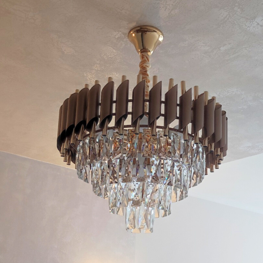 Стельова люстра з підвісками з кристалів та коричневим каркасом, встановлена ​​у світлій вітальні з декоративною стелею; класичний дизайн підкреслює стиль інтер'єру, фото від клієнта з Івано-Франківська