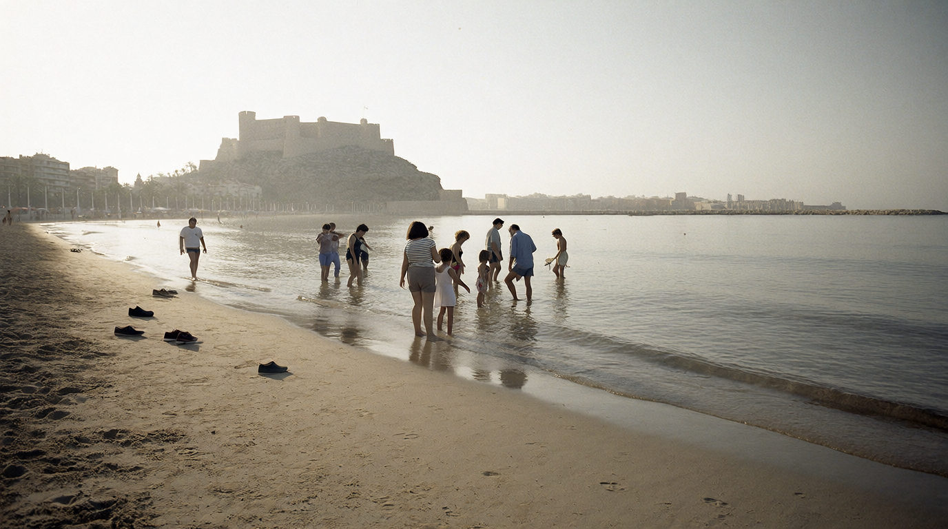 People paddling at Postiguet beach at dawn with Santa Bárbara castle above the Alicante seafront