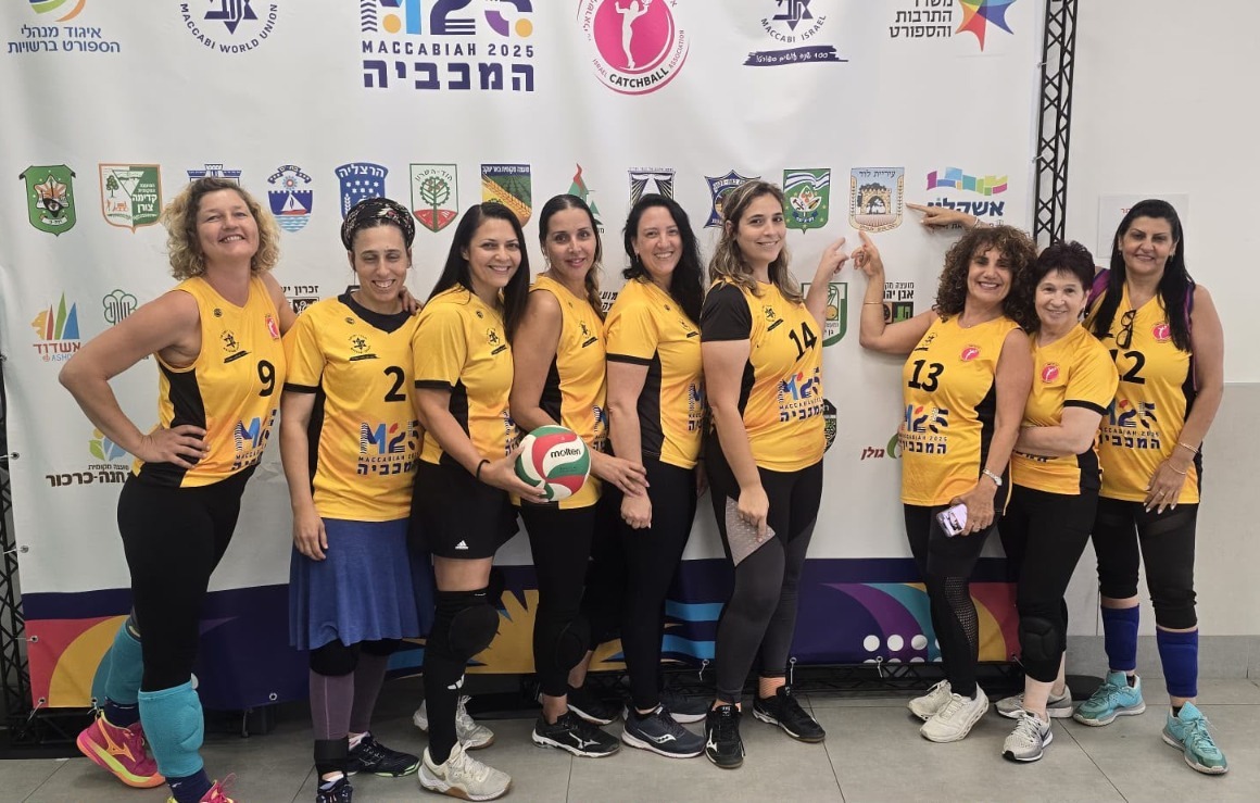 שחקניות קבוצת הכדורשת של לוד למכביה מצביעות בגאווה על סמל העיר