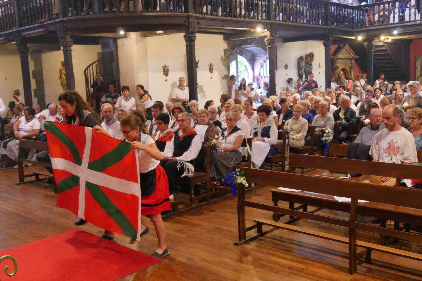 Procession des offrandes ouverte par le drapeau basque ; accompagnée par l'orchestre avec "Largo" de R. Zugarramurdi