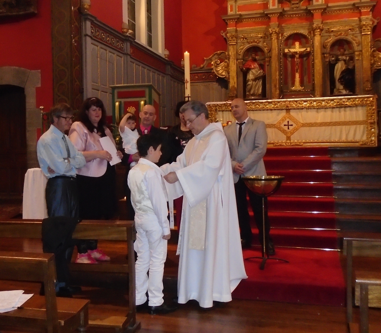 Le prêtre revêt le néophyte du vêtement blanc, une écharpe brodée des signes chrétiens et au nom de Eusko