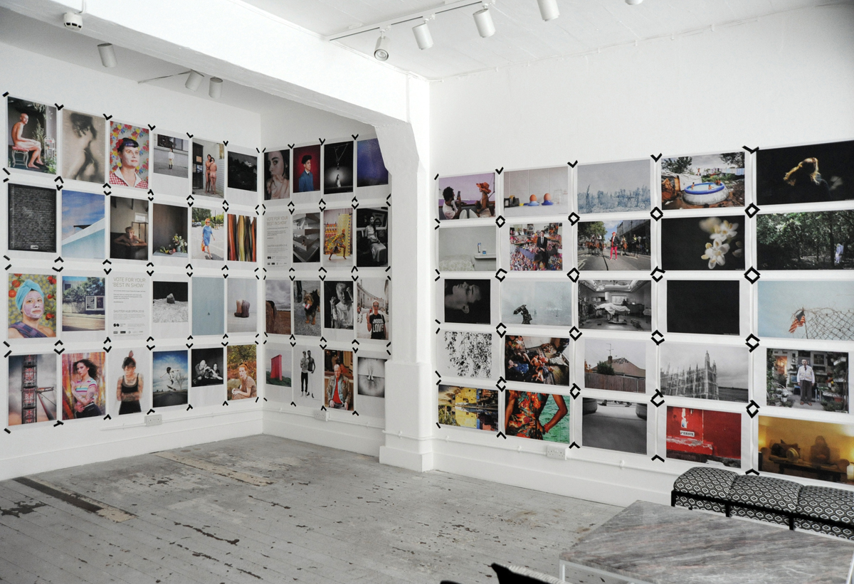 Shutter Hub OPEN exhibition 2018 - gallery space in the Old Truman Brewery, walls covered with newsprint photographs taped to the walls