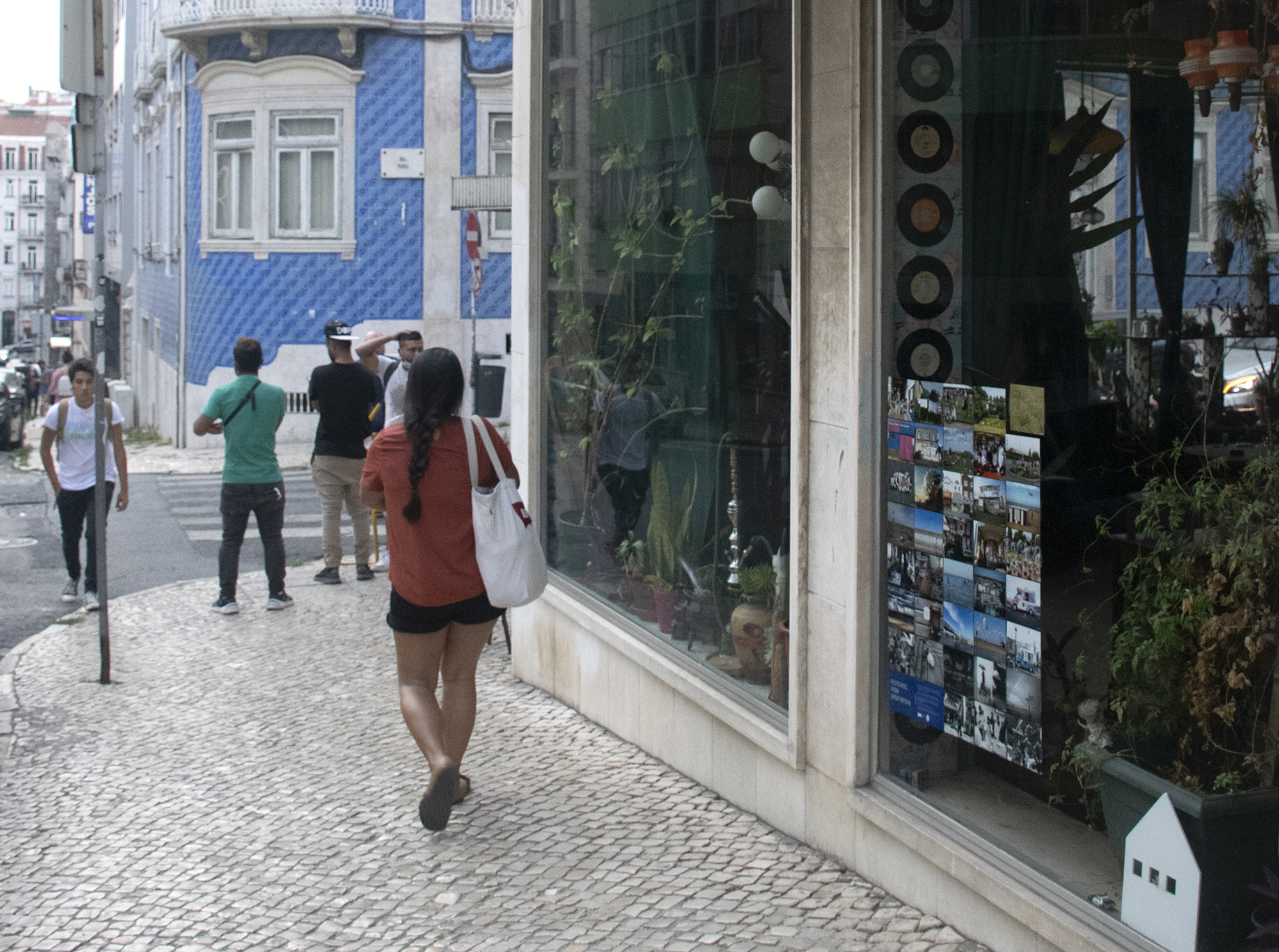 A street in Lisbon, Portugal. In one of the shop windows there is an exhibition of Shutter Hubs Postcards from Great Britain project, lots of postcard sized photographs