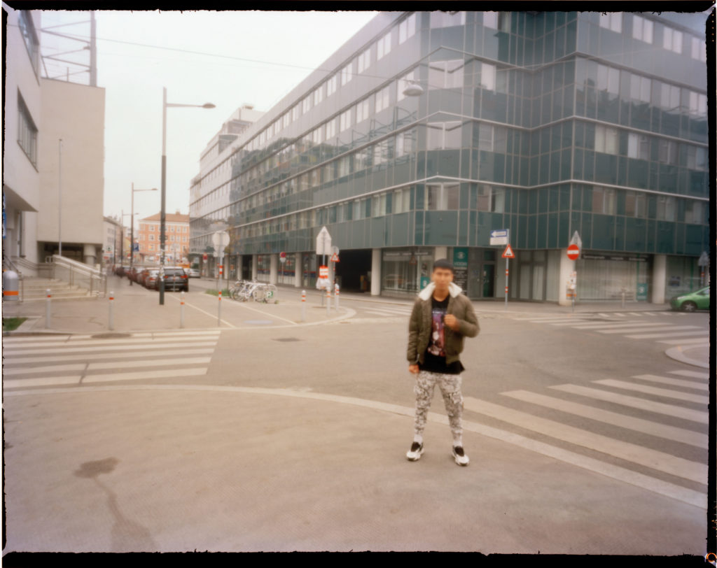 A male out of focus refugee is photographed outside a modern building that is the central police station in Vienna.