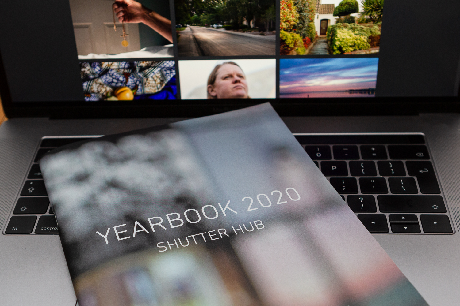 The YEARBOOK 2020 publication lying on the keyboard of a laptop, with images from the online exhibition on the screen behind.
