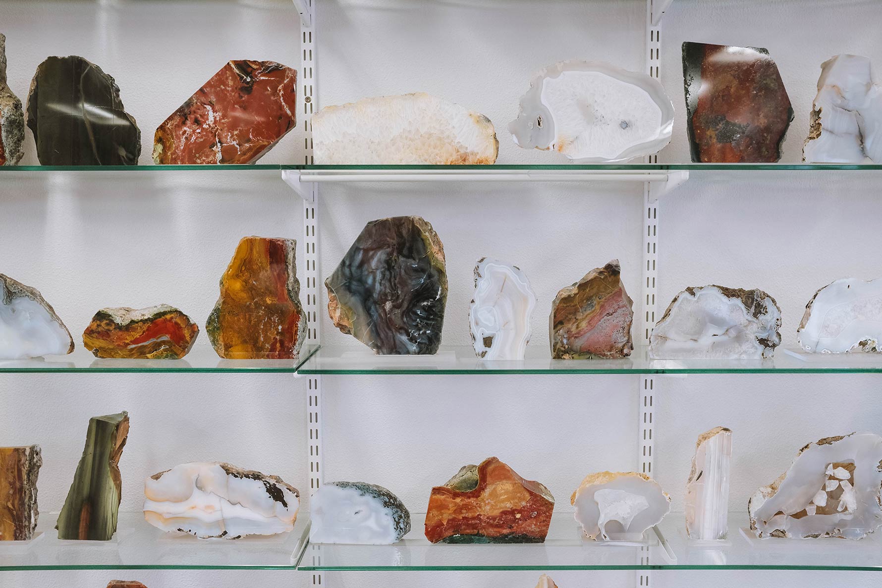 Cut and polished stones arranged on glass shelves inside Audunn's Mineral Collection.