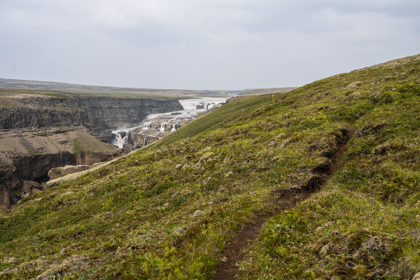 Narrow highland footpath with Dynkur waterfall visible across the canyon.