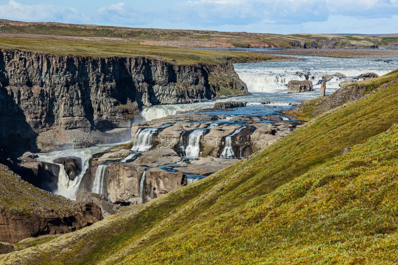 Official regional view of Dynkur with green highland slopes above Þjórsá.