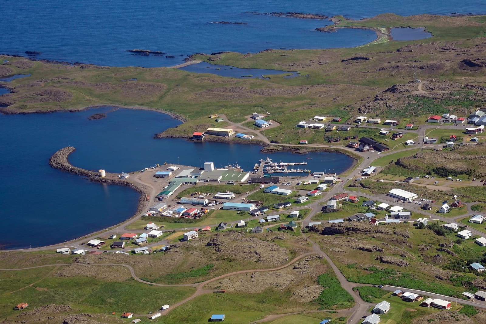 Aerial view of Djúpivogur harbor, town buildings, coastline, and mountains in East Iceland.