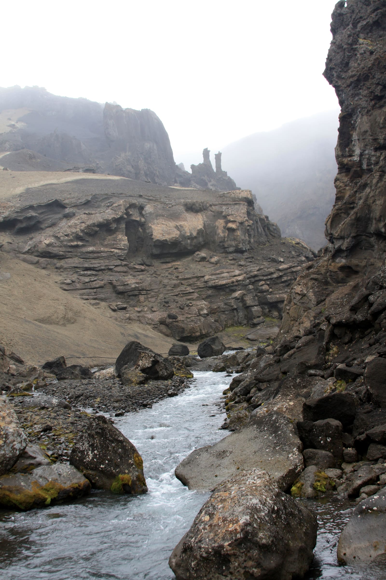 Rocky river corridor between layered volcanic walls in Drekagil.