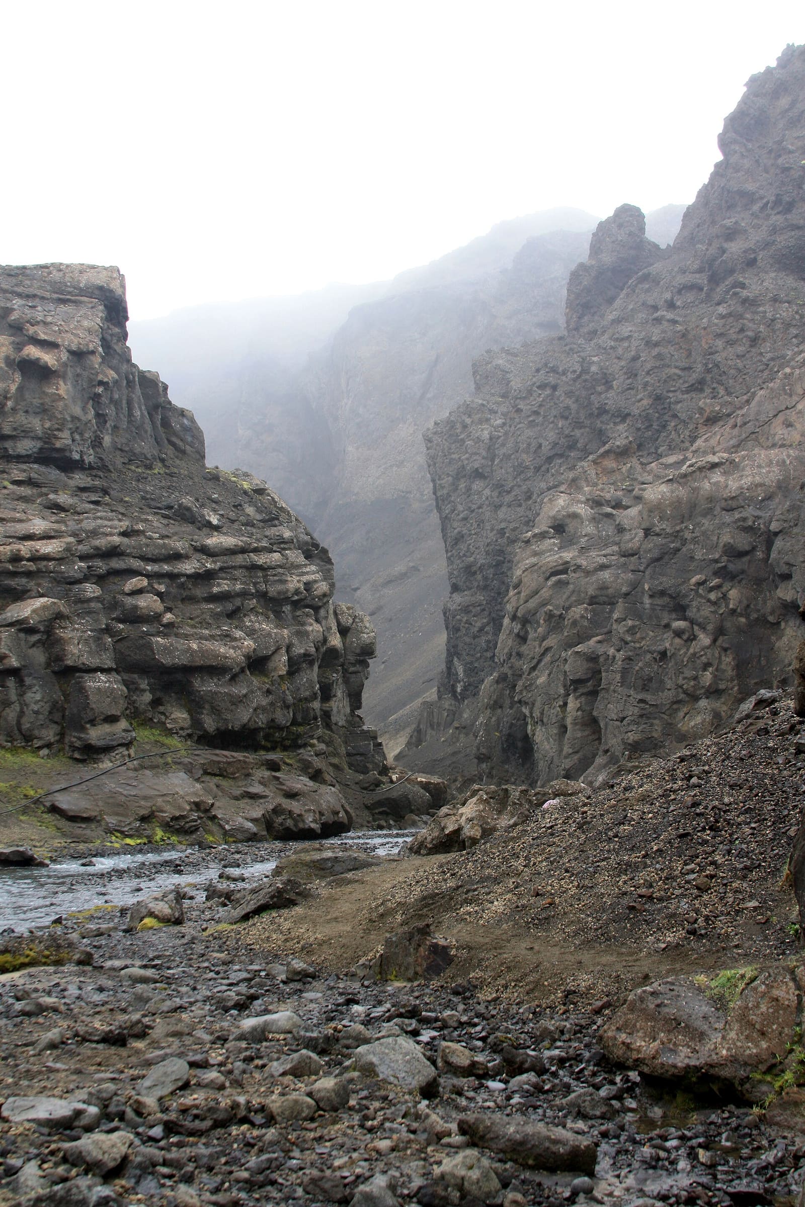 Narrow Drekagil gorge walls towering above a rocky stream bed.