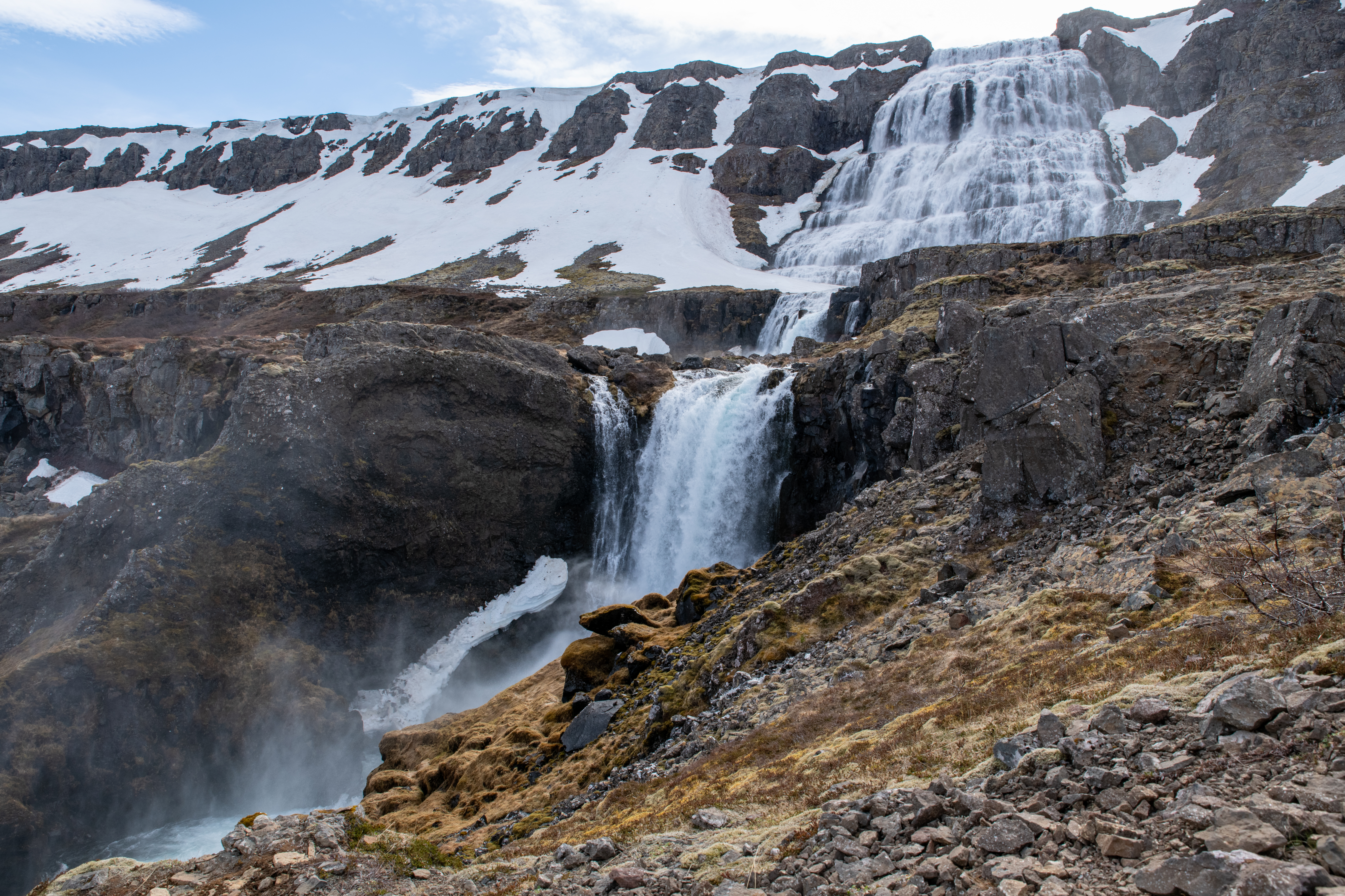 Dynjandi waterfall with snow patches on the surrounding Westfjords cliffs.
