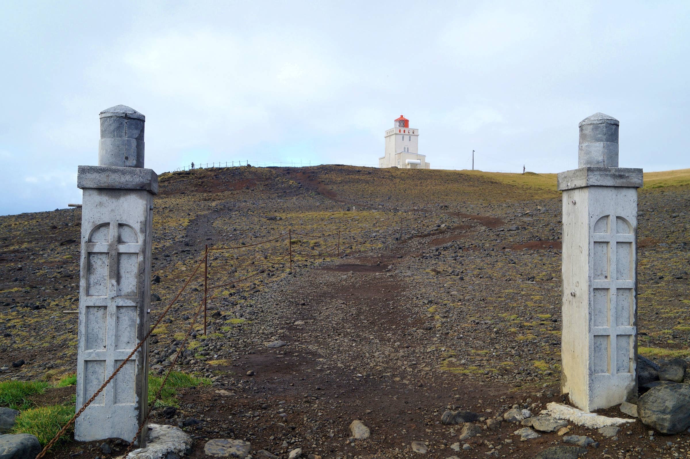 Path and gate leading toward Dyrhólaey Lighthouse on the upper headland.