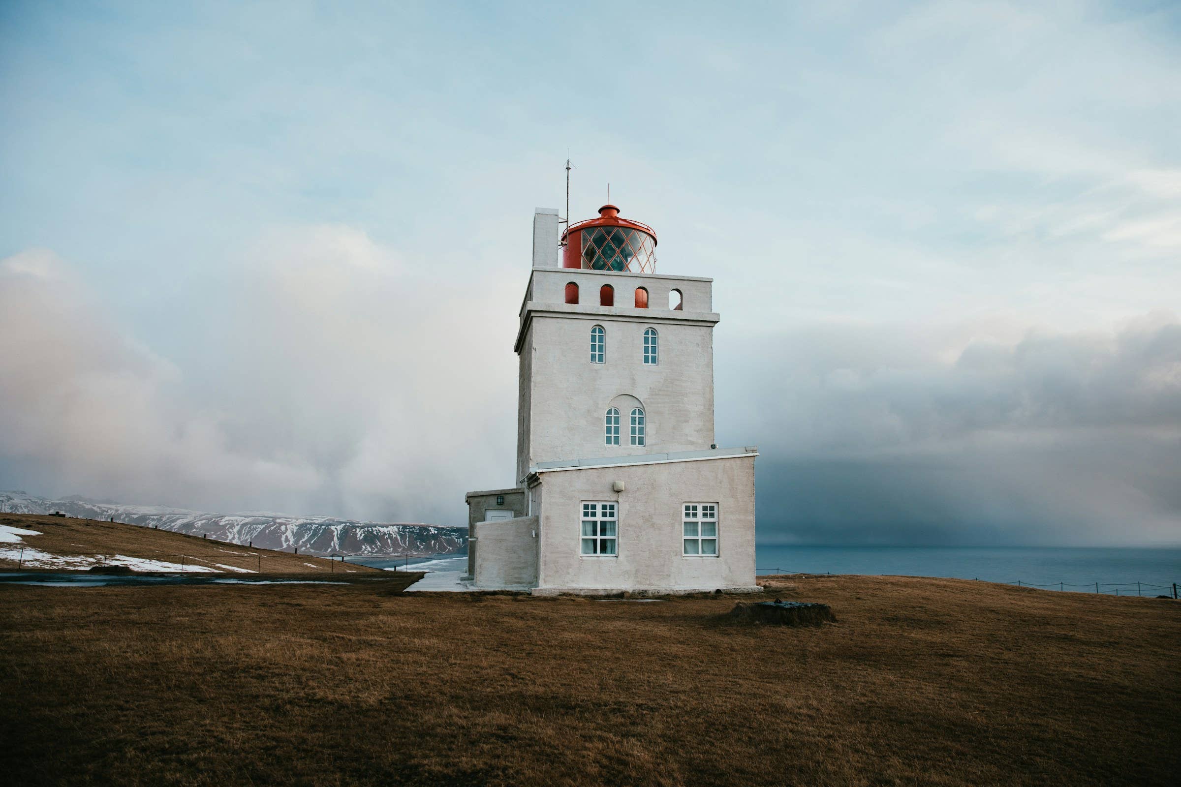 Dyrhólaey Lighthouse facing winter-colored cliffs and Atlantic weather.