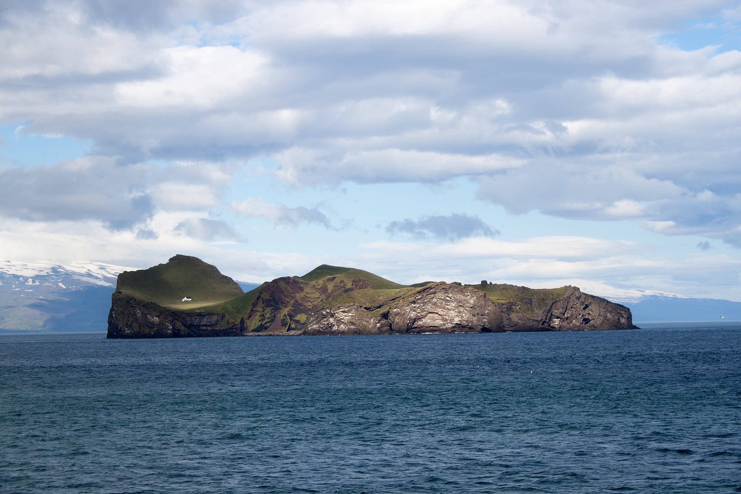 Ellidaey Island cliffs and green slopes in the Vestmannaeyjar archipelago.