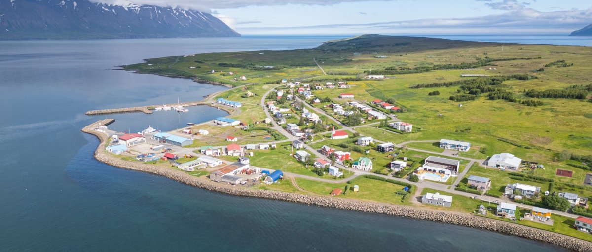 Aerial view of Hrísey island in Eyjafjörður with the village and fjord shoreline visible.