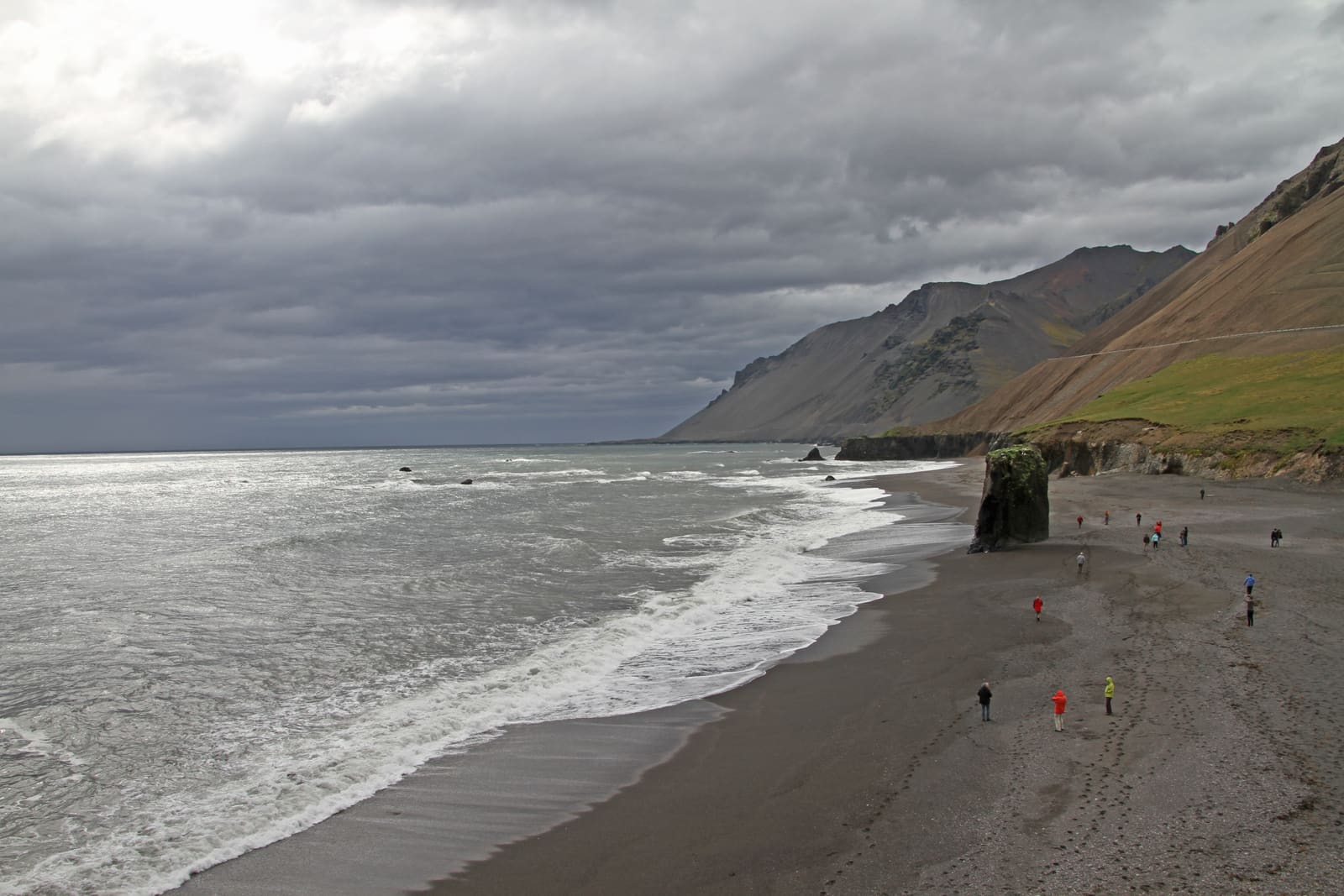 Fauskasandur Black Sand Beach with surf, a sea stack, and steep mountains near Hvalnes in East Iceland.