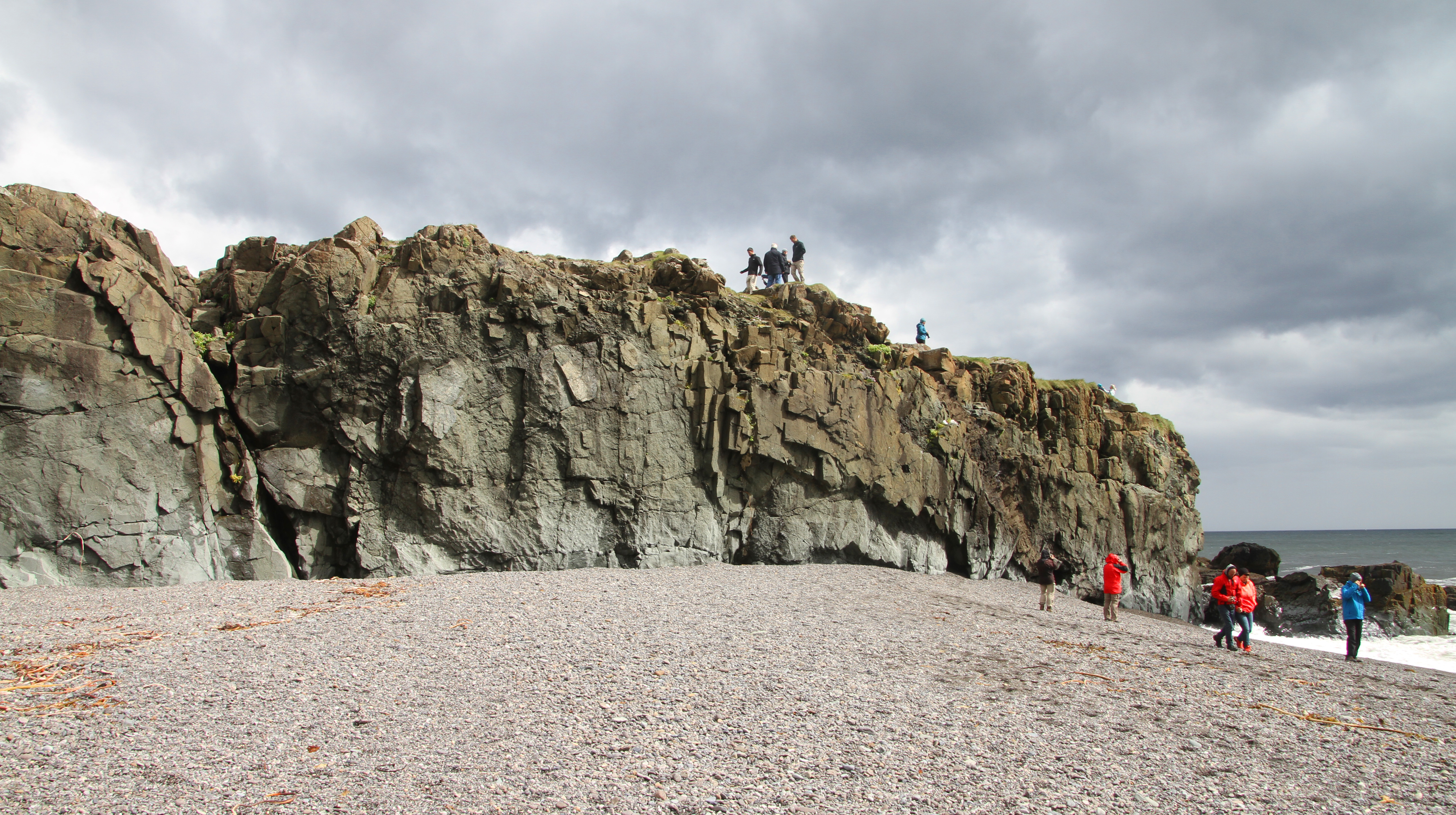 Rocky sea cliffs and coarse dark beach texture at Fauskasandur in East Iceland.