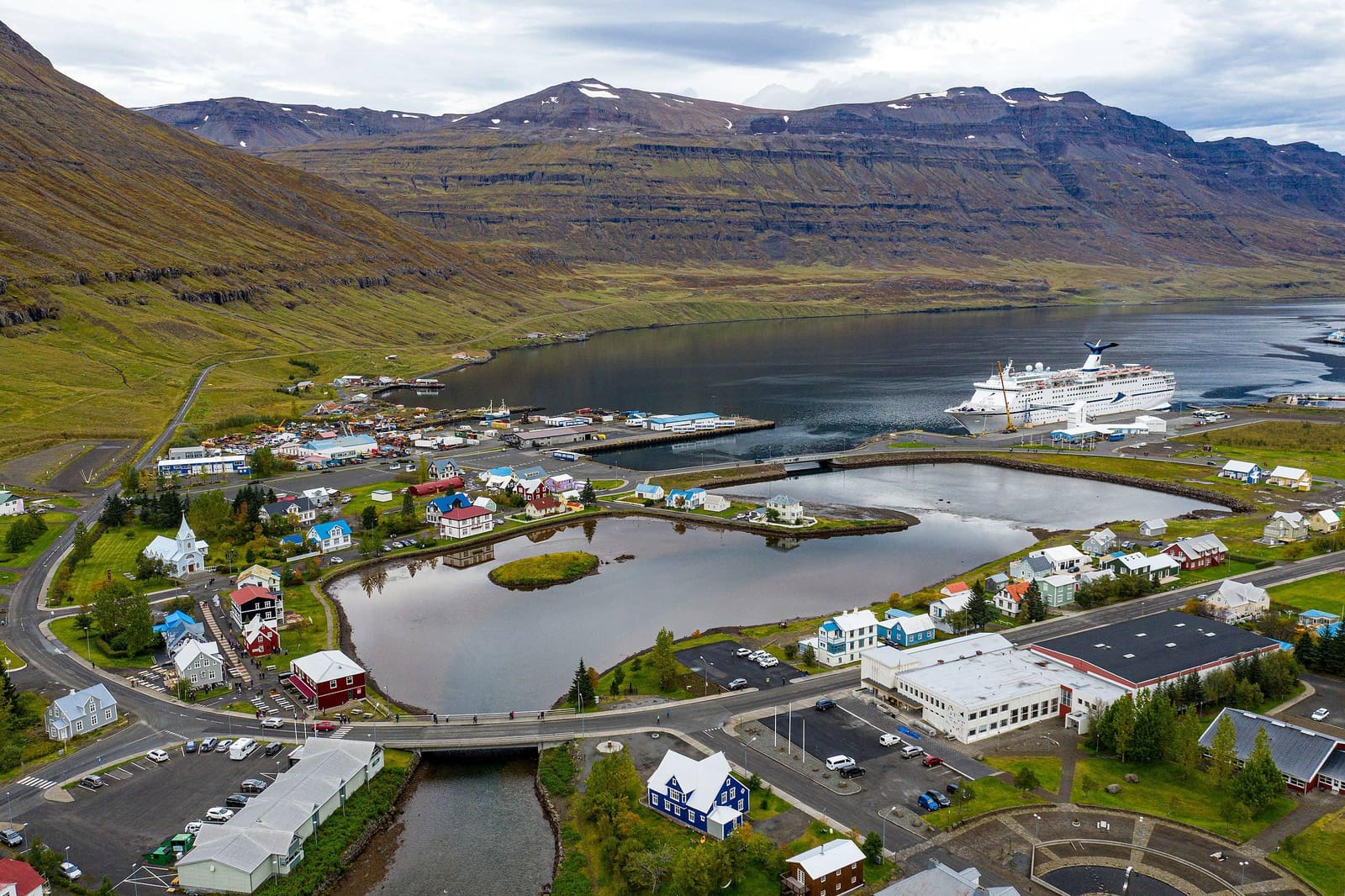 Fjardara Lake beside Seydisfjordur with colorful buildings and fjord slopes.