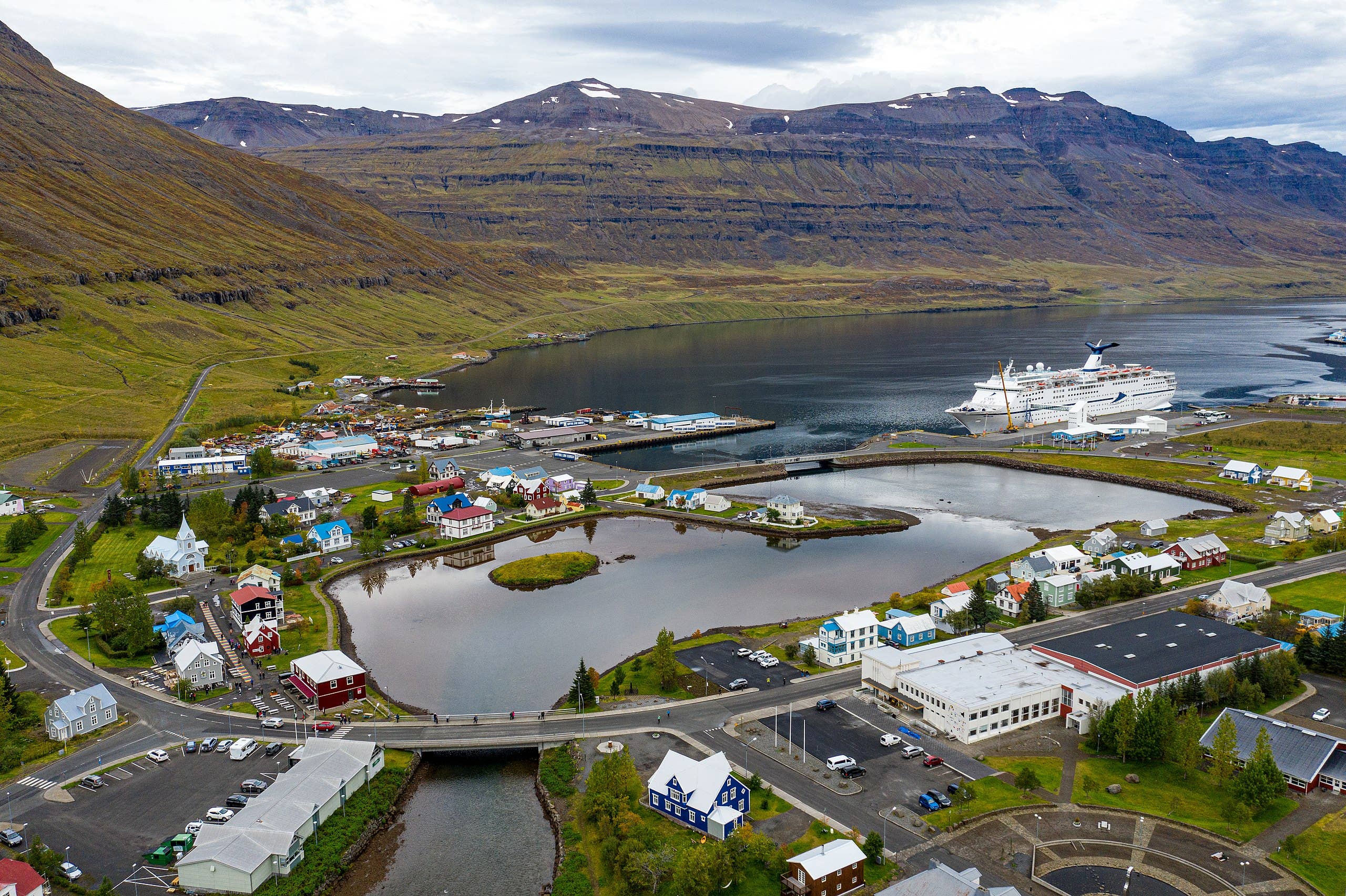 Fjardara Lake beside Seydisfjordur with colorful buildings and fjord slopes.