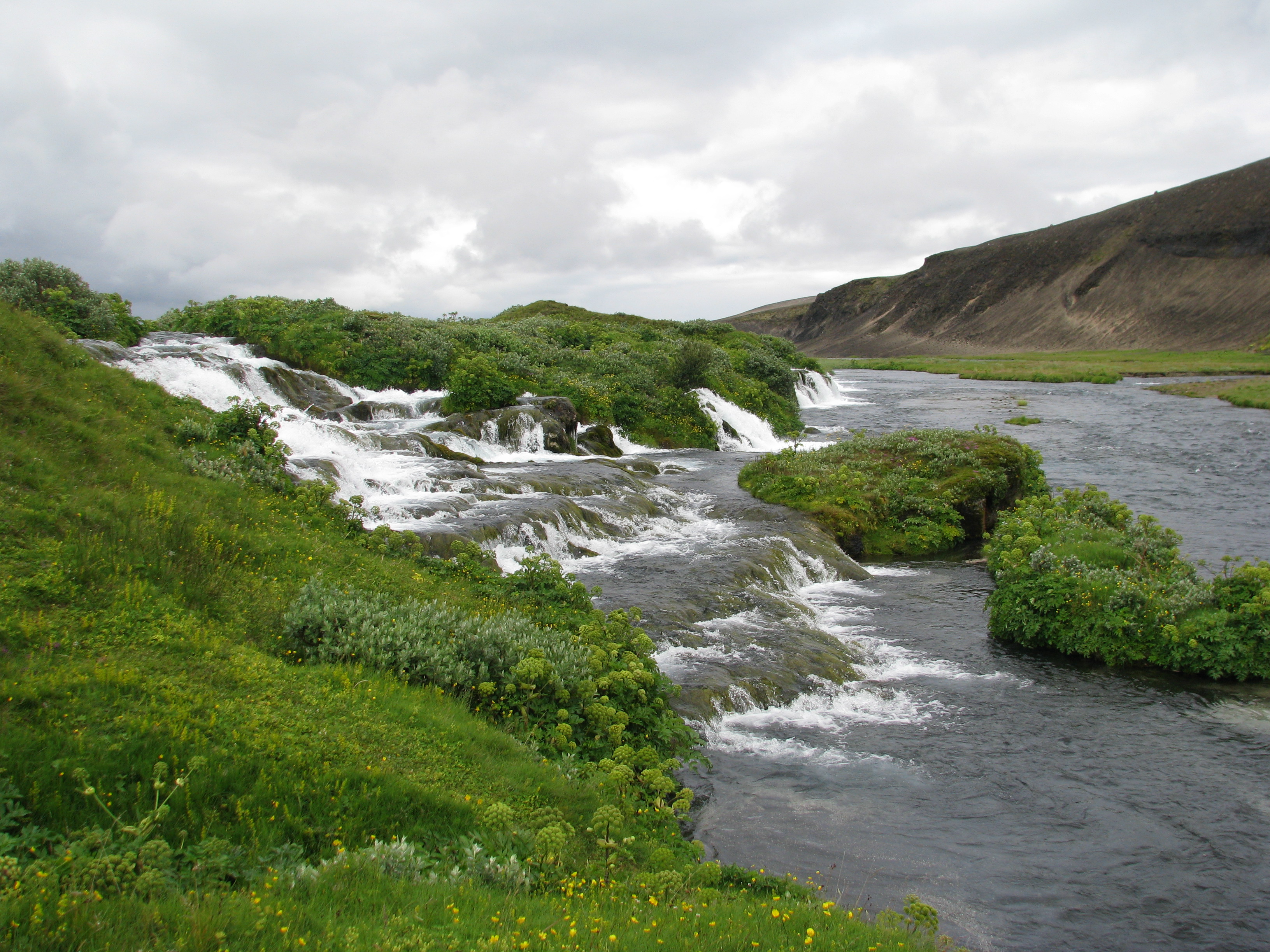 Fossbrekkur waterfall and green river slope in the upper Ytri-Rangá area.