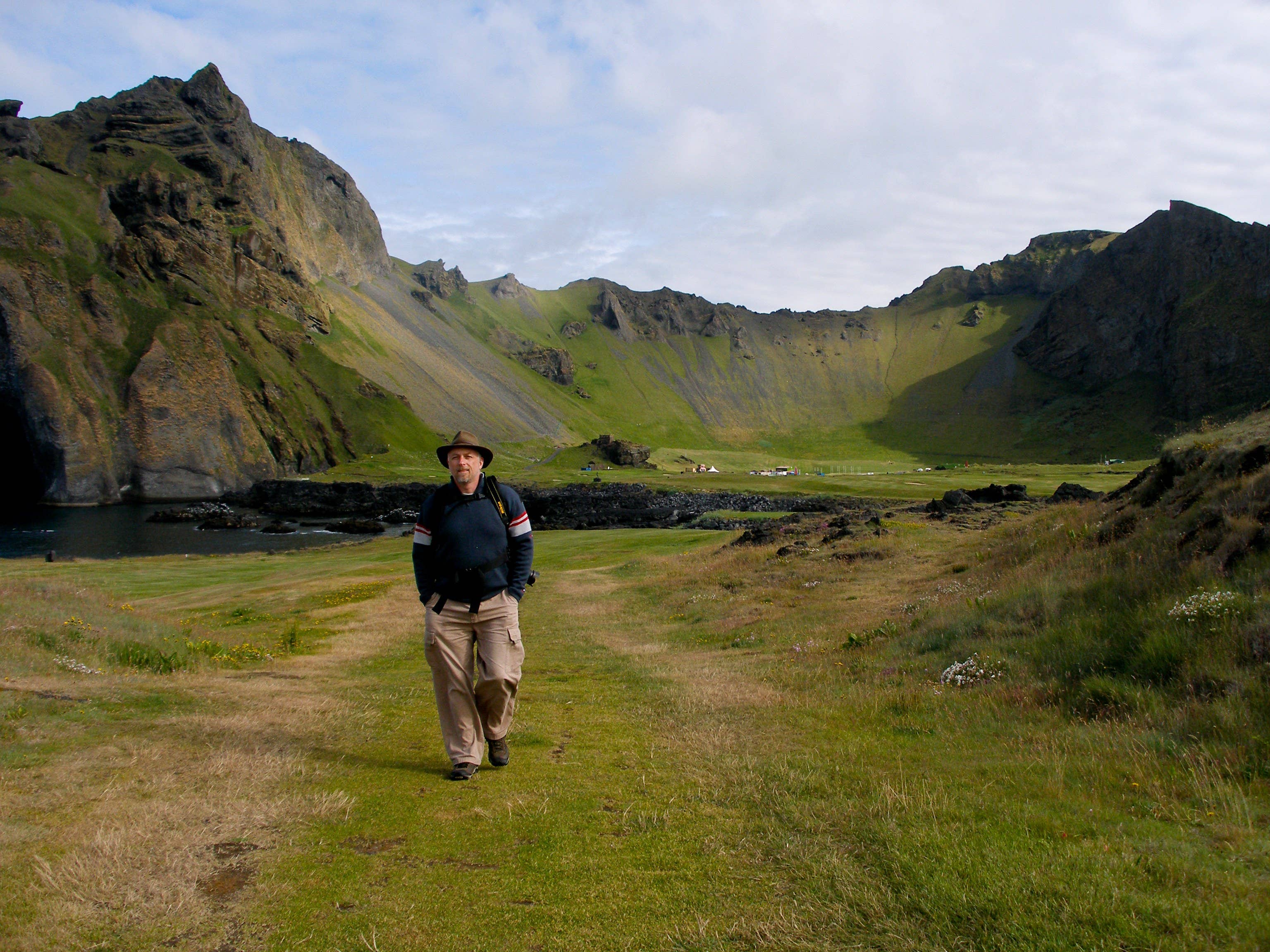 Traveler standing in the grassy floor of Herjolfsdalur Valley on Heimaey.