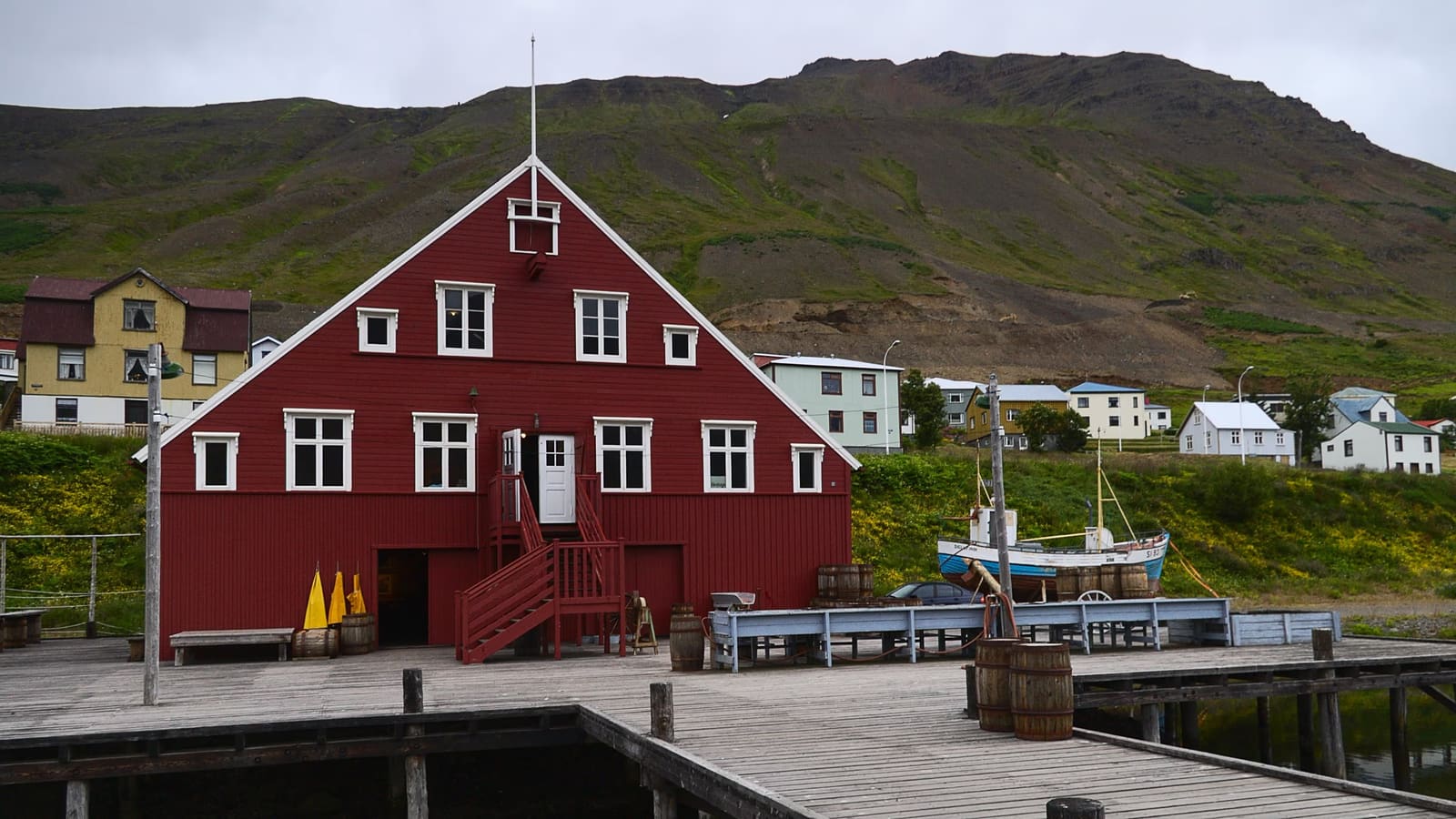 Herring Era Museum buildings in Siglufjörður with mountains behind the harbor.