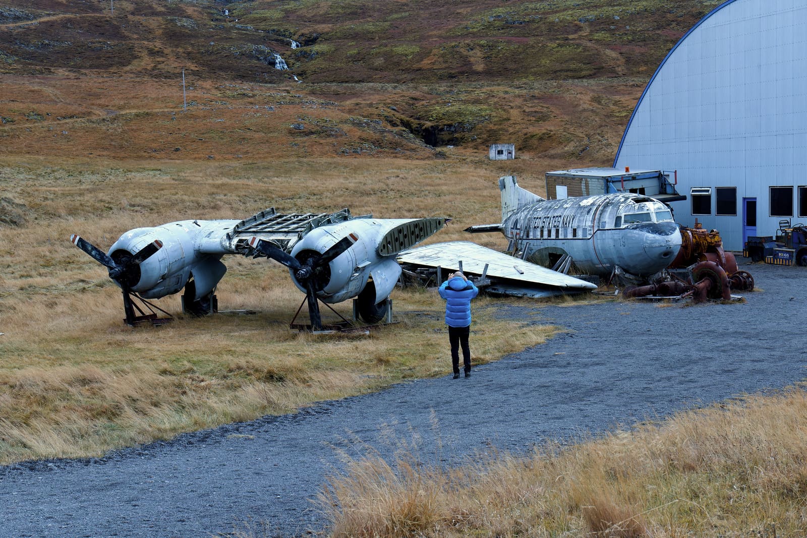 Visitor photographing a retired aircraft outside Hnjótur Museum in Iceland.