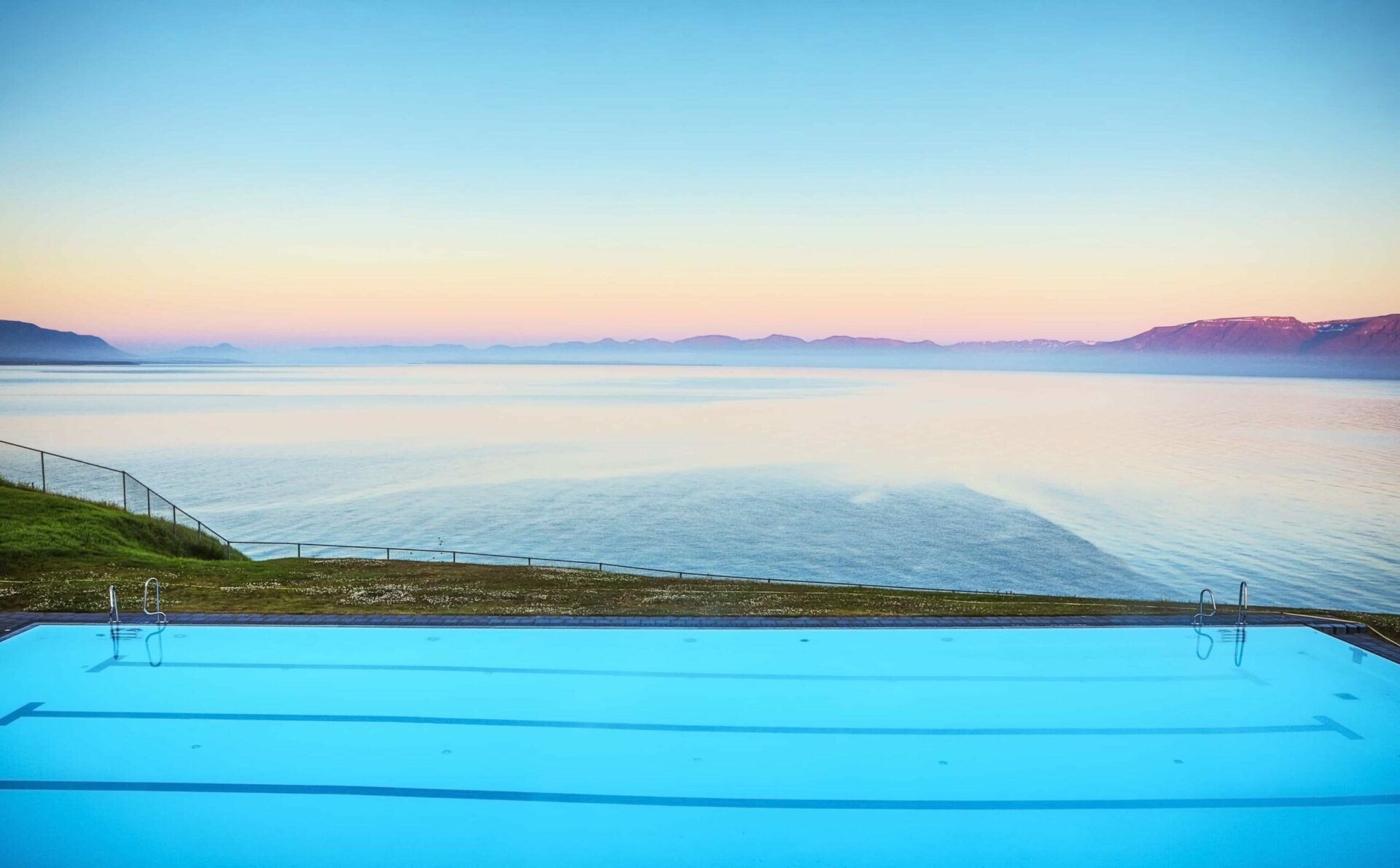 Hofsós Swimming Pool seen from another poolside angle with mountains behind the water.