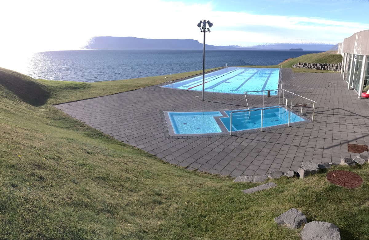 The Hofsós pool edge looking across Skagafjörður toward distant mountains.