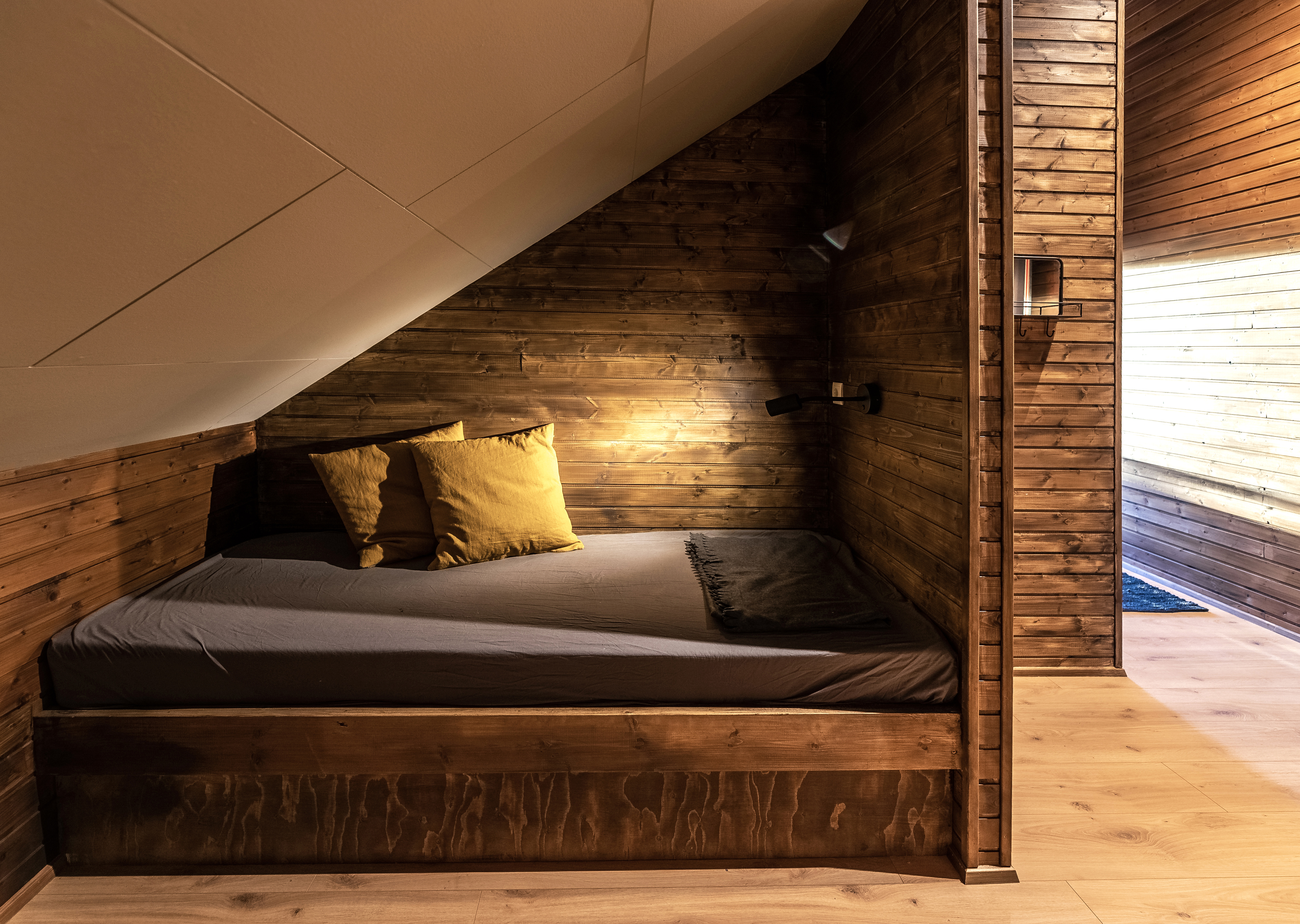 Wood-lined sleeping space inside Hólaskógur mountain lodge.
