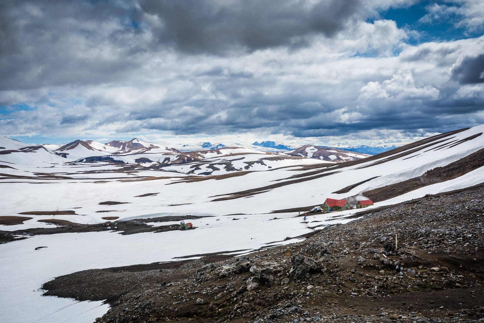 Red Hrafntinnusker hut below snow-covered Highlands slopes on the Laugavegur Trail.