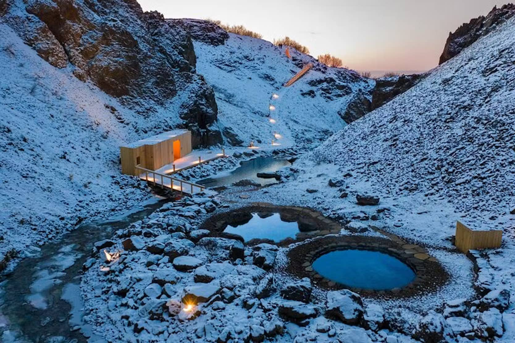 Húsafell Canyon Baths in winter with snow around the stone pools and canyon walls.