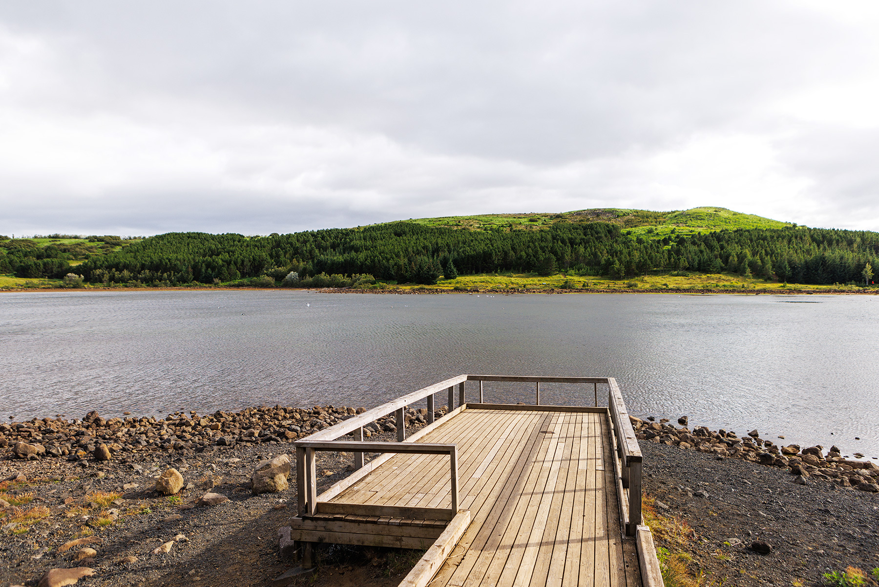 Hvaleyrarvatn shoreline and gravel walking route beside forested hills