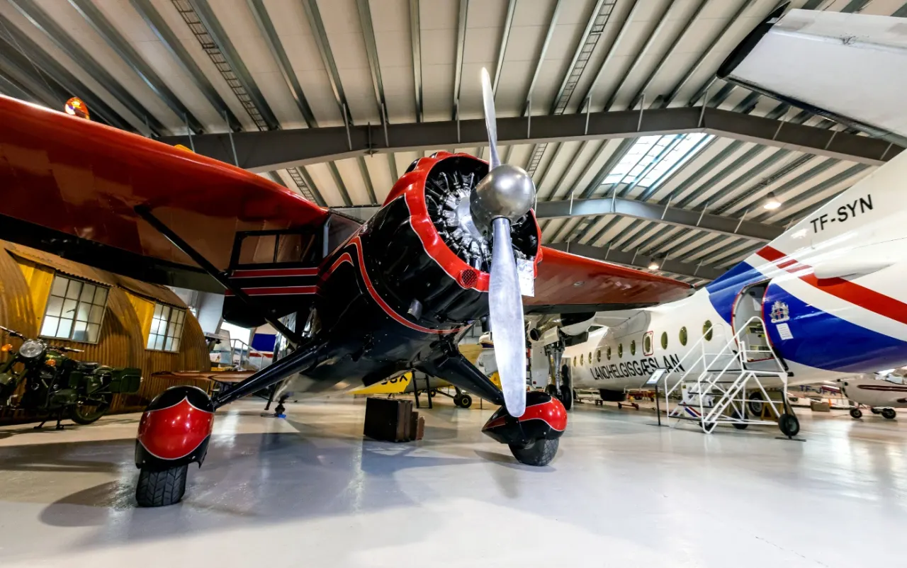 Red historic aircraft displayed inside the Icelandic Aviation Museum hangar.