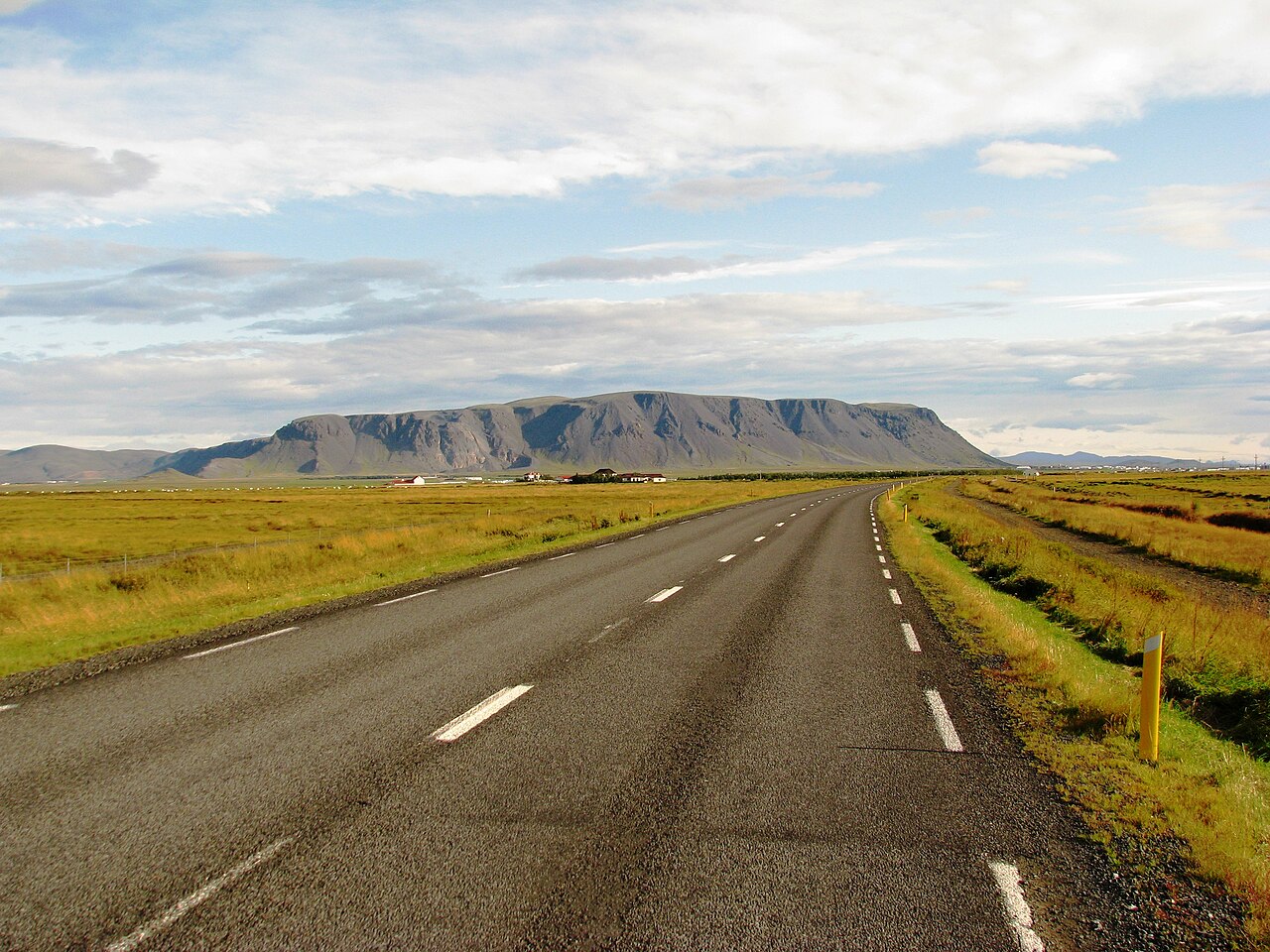 Broad side of Ingólfsfjall above low South Iceland farmland.